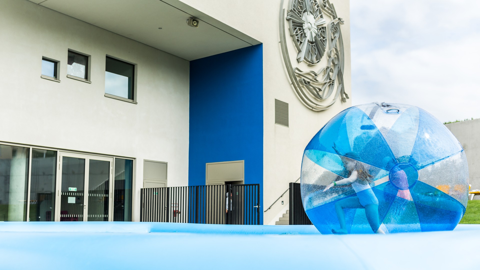 Kleines Mädchen im Zorbingball auf dem Wasser neben dem blu auf der Spielewiese, © SekundenstillFotgrafie