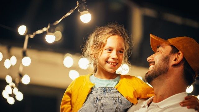 Vater und Tochter klatschen in die Hände, darüber ist eine Lichterkette, © AdobeStock_558713714